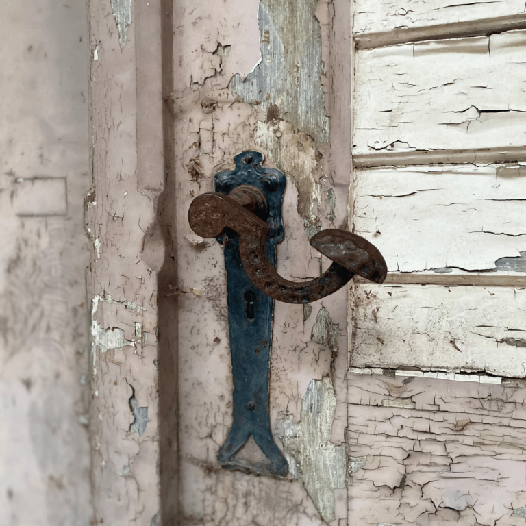 Ein alter Türgriff an einer verwitterten Holztür